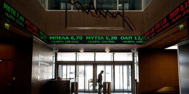 A man walks at the reception hall of the Athens' Stock Exchange as stock prices are on display on a ticker screen in Athens, Greece, on Tuesday, Aug. 4, 2015. The Stock Exchange is suffering a second day of losses after reopening amid capital controls, with banks again suffering the worst damage. (AP Photo/Yorgos Karahalis)