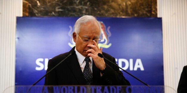 Malaysian Prime Minister Najib Razak, center, gestures before speaking at a special press conference announcing the findings for the ill fated flight MH370 in Kuala Lumpur, Malaysia, early Thursday, Aug. 6, 2015. Experts have confirmed that the debris found on Reunion Island last week was that of Malaysian Airlines flight 370 that went missing last year, Malaysia's prime minister said early Thursday. (AP Photo/Vincent Thian)