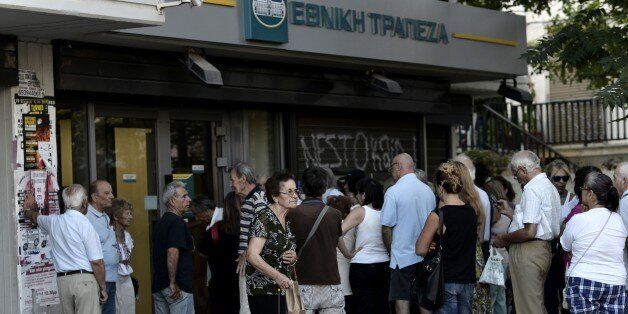 People wait to enter a bank, prior its opening on July 20, 2015 in Athens. Greek banks reopened on July 20 after a shutdown lasting three weeks imposed by the government to avert a crash in the banking system over the country's debt crisis. However, capital controls in force since June 29 remain in place, although a daily cash withdrawal limit of 60 euros ($65.03) has now been relaxed to a weekly restriction of 420 euros. AFP PHOTO / ARIS MESSINIS (Photo credit should read ARIS MESSINIS/AFP/Getty Images)