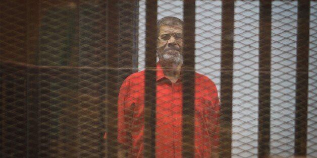 CAIRO, EGYPT - AUGUST 10: Former Egyptian President Mohamed Morsi stands inside the defendants' cage in a courtroom at the police academy during his trial over espionage with Qatar on August 10, 2015 in Cairo, Egypt. (Photo by Mohamed Jamil/Anadolu Agency/Getty Images)
