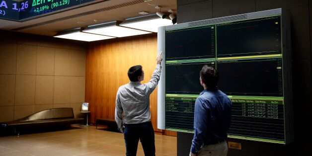 Two men check an index board at the reception hall of the Athens' Stock Exchange, in Athens, Greece, Tuesday, Aug. 4, 2015. The Stock Exchange is suffering a second day of losses after reopening amid capital controls, with banks again suffering the worst damage. (AP Photo/Yorgos Karahalis)