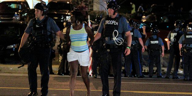 Officers arrest a protester, Monday, Aug. 10, 2015, in Ferguson, Mo. Ferguson was a community on edge again Monday, a day after a protest marking the anniversary of Michael Brown's death was punctuated with gunshots. (AP Photo/Jeff Roberson)