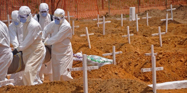 Health workers carry the body, of a person that they suspected died from the Ebola virus at a new graveyard on the outskirts of Monrovia, Liberia, Wednesday, March 11, 2015. Liberians held a church service Wednesday for families who lost members to Ebola to mark the countryâs 99th celebration National Decoration Day, a holiday normally set aside for people to clean up and re-decorate the graves of their lost relatives. (AP Photo/Abbas Dulleh)