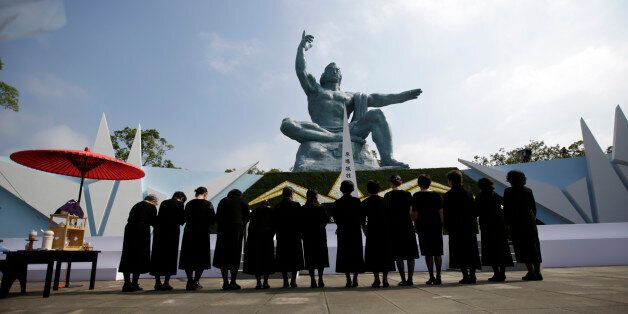 Visitor bow in front of the Peace Statue at the 70th anniversary of the atomic bombing in Nagasaki, southern Japan Sunday, Aug. 9, 2015. (AP Photo/Eugene Hoshiko)