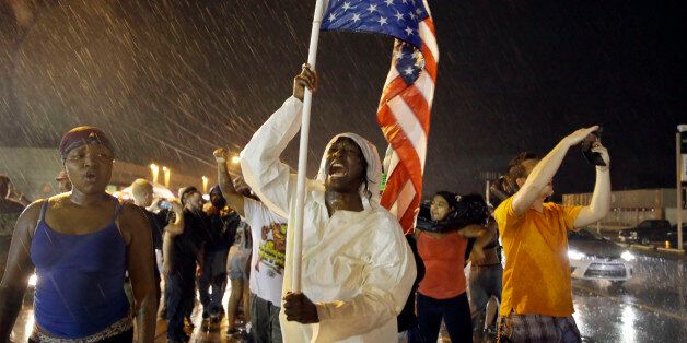 Protesters march in the rain, Sunday, Aug. 9, 2015, in Ferguson, Mo. Sunday marks one year since Michael Brown was shot and killed by Ferguson Police Officer Darren Wilson. (AP Photo/Jeff Roberson)
