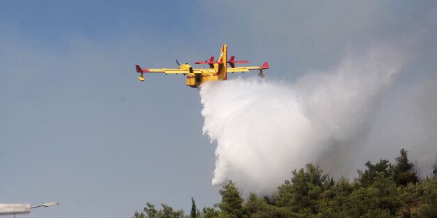 A Canadair drops water on a forest fire at the Thessaloniki Seih Sou park, which overlooks the city of Thessaloniki, on July 14, 2012. The risk of new fires was considered high, after several days of hot temperatures accross most of Greece. AFP PHOTO /SAKIS MITROLIDIS (Photo credit should read SAKIS MITROLIDIS/AFP/GettyImages)