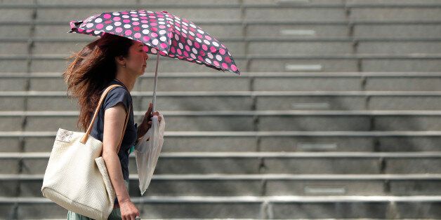A woman uses an umbrella to shelter from the sun in Tokyo, Japan, on Monday, July 13, 2015. The Japan Meteorological Agency reported that Tokyo area recorded a temperature of 33.6 degrees on July 13. Photographer: Kiyoshi Ota/Bloomberg via Getty Images