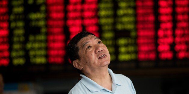 An investor monitors screens showing stock market movements at a brokerage house in Shanghai on August 13, 2015. Shanghai shares were down 0.62 percent, 24.26 points to 3,862.06, by the break on August 13, after China set a lower value for its yuan currency for the third straight day. China cut the reference rate for its currency for the third straight day on August 13, authorities said, after their surprise devaluation of the yuan this week unsettled global financial markets. AFP PHOTO /