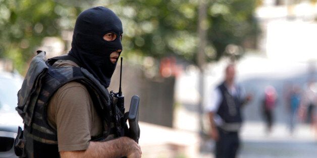 A masked Turkish police officer secures a road leading to the U. S. Consulate building in Istanbul, Monday, Aug. 10, 2015. Two assailants opened fire at the building on Monday, touching off a gunfight with police before fleeing the scene, Turkish media reports said. (AP Photo/Lefteris Pitarakis)