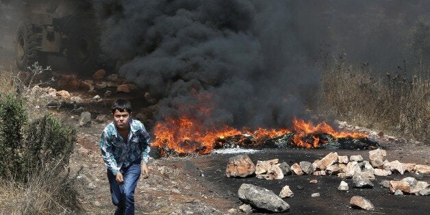 A Palestinian boy runs amid the smoke of burning tires during clashes between Palestinian protesters and Israeli security forces following a demonstration against the expropriation of Palestinian land by Israel in the village of Kfar Qaddum, near Nablus, in the occupied West Bank, on August 7, 2015. AFP PHOTO / JAAFAR ASHTIYEH (Photo credit should read JAAFAR ASHTIYEH/AFP/Getty Images)