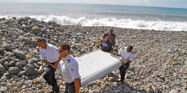 In this photo dated Wednesday, July 29, 2015, French police officers carry a piece of debris from a plane in Saint-Andre, Reunion Island. Air safety investigators, one of them a Boeing investigator, have identified the component as a