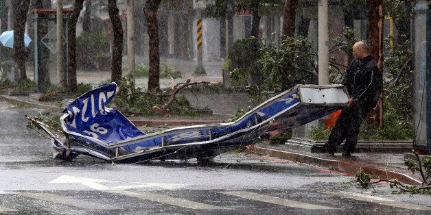 A man drags a sign brought down by strong winds from Typhoon Soudelor in Taipei, Taiwan, Saturday, Aug. 8, 2015. Soudelor brought heavy rains and strong winds to the island Saturday with winds speeds over 170 km per hour (100 mph) and gusts over 200 km per hour (120 mph) according to Taiwan's Central Weather Bureau. (AP Photo/Wally Santana)