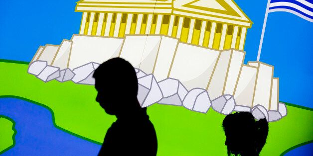 A couple walk in front of a picture displaying the Parthenon, an iconic ancient temple, and the Greek flag in central Athens, Thursday, June 25, 2015. The ECB approved a request from Athens to increase the amount of emergency liquidity Greek lenders can tap from the country's central bank. Worried Greeks have been withdrawing their money from their country's banks, fearing the imposition of restrictions on banking transactions. An estimated more than 4 billion euros ($4.5 billion) left Greek banks last week. (AP Photo/Daniel Ochoa de Olza)