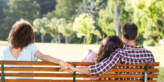 Lonely woman sitting with couple in park on a sunny day