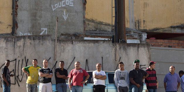 Residents stand across the street from a bar where at least 10 people were shot the night before, in the Sao Paulo suburb Osasco, Brazil, Friday, Aug. 14, 2015. Police in Brazil's biggest city are investigating the shooting deaths of at least 17 people within the span of about three hours. According to police the 10 people were shot dead after hooded men got out of a car and opened fire. (AP Photo/Andre Penner)