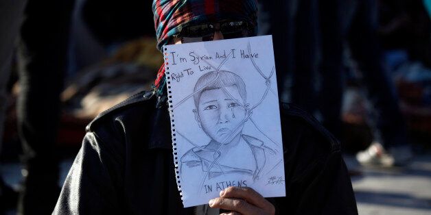 A Syrian refugee holds a sketch as he protests at central Syntagma square, outside the Greek parliament in Athens on Sunday, Dec. 14 2014. About 150 Syrian civil war refugees began a hunger strike in front of Greece's Parliament three weeks ago, urging the government to grant them temporary working and residence rights. Greece is a busy entry point for immigrants and refugees seeking entry to the European Union. The financial crisis-hit country has seen a spike in the number of Syrians crossing