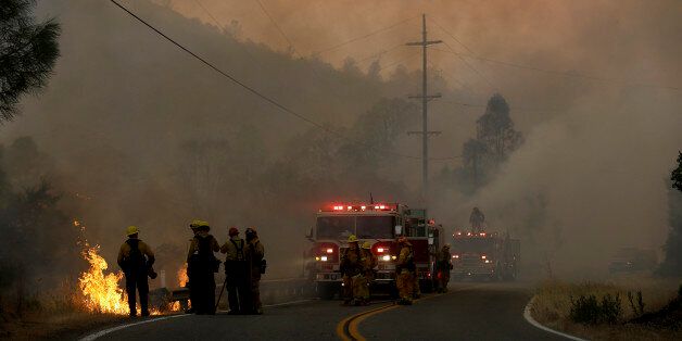 Firefighters tend to a back fire operation at left under smoke from fires along Morgan Valley Road near Lower Lake, Calif., Friday, July 31, 2015. A series of wildfires were intensified by dry vegetation, triple-digit temperatures and gusting winds. (AP Photo/Jeff Chiu)