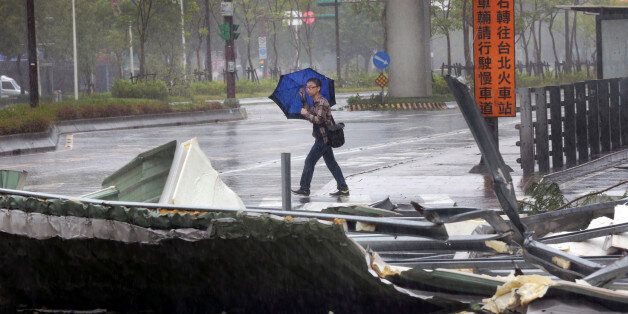A man carrying an umbrella passes a mangled rooftop brought down by strong winds from Typhoon Soudelor in Taipei, Taiwan, Saturday, Aug. 8, 2015. Soudelor brought heavy rains and strong winds to the island Saturday with winds speeds over 170 km per hour (100 mph) and gusts over 200 km per hour (120 mph) according to Taiwan's Central Weather Bureau. (AP Photo/Wally Santana)