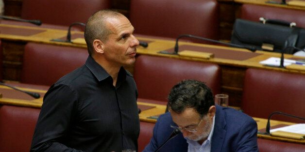 Lawmaker Yanis Varoufakis, left, holds a glass of water as he passes by Panagiotis Lafazanis, a parliament member of Syriza governing party, during a parliament committee in Athens, Wednesday, July 22, 2015. Greece's parliament has begun an emergency debate on a second round of conditions demanded by international creditors for a new bailout - a vote that could threaten the coalition government. (AP Photo/Thanassis Stavrakis)