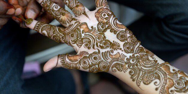 An Indian girl has decorative henna designs applied to her hands at a roadside stall ahead of the Muslim holiday of Eid al-Fitr which marks the end of Ramadan in Mumbai on July 17, 2014. Muslims around the world have started to celebrate the Eid al-Fitr holiday, which marks the end of the fasting month of Ramadan. AFP PHOTO/ INDRANIL MUKHERJEE (Photo credit should read INDRANIL MUKHERJEE/AFP/Getty Images)