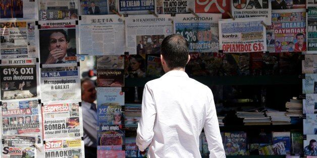 A man reads the front pages of the Greek newspapers in Athens, Monday, July 6, 2015. Greek Finance Minister Yanis Varoufakis resigned Monday, saying he was told shortly after Greece's decisive referendum result that some other eurozone finance ministers and the country's other creditors would appreciate his not attending the ministers' meetings. (AP Photo/Petr David Josek)