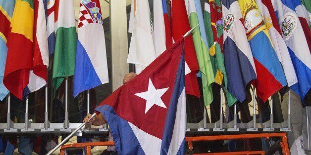 A workman at the US Department of State add the Cuban flag at to the display of flags inside the main entrance at 202 'C' Street at 4am local time (0800 GMT) in Washington, DC on July 20, 2015. The United States and Cuba formally resumed diplomatic relations on July 20, as the Cuban flag was raised at the US State Department in a historic gesture toward ending decades of hostility between the Cold War foes. AFP PHOTO / Paul J. Richards (Photo credit should read PAUL J. RICHARDS/AFP/G