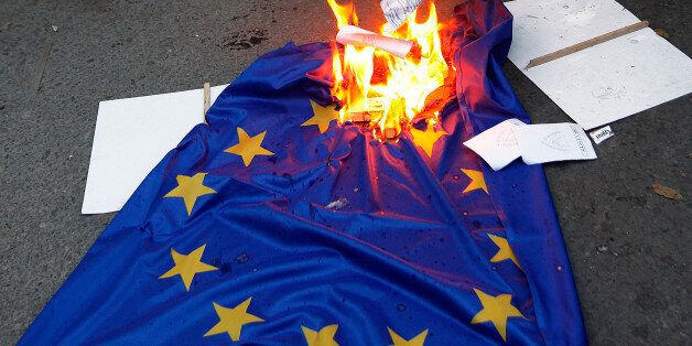 Protesters burn an EU flag during an anti-bailout protest outside of Cyprus' parliament in Nicosia, Tuesday, April 30, 2013. Cyprus' lawmakers are voting Tuesday on a multi-billion bailout agreement aimed at preventing the country from going bankrupt. The 56-seat parliament is expected to narrowly approve the 23 billion-euro ($30 billion) deal that the country struck with its euro partners and the International Monetary Fund last month. (AP Photo/Petros Karadjias)
