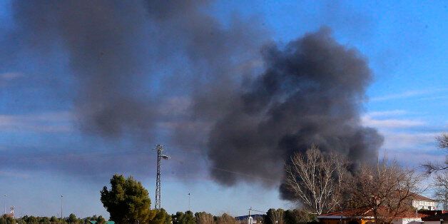 Smoke rises from a military base after a plane crash in Albacete, Spain, Monday, Jan. 26, 2015. A Greek F-16 fighter jet crashed into other planes on the ground during NATO training in southeastern Spain Monday, killing at least 10 people, Spain's Defense Ministry said. Another 13 people were injured in the incident at the Los Llanos base, which sent flames and a plume of black smoke billowing into the air, a Defense Ministry official said. (AP Photo/Josema Moreno)