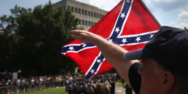 COLUMBIA, SC - JULY 18: A member of the Ku Klux Klan gives a Nazi salute as the Klan members fly the Confederate flag during a demonstration at the state capitol building on July 18, 2015 in Columbia, South Carolina. Hundreds of people protested the demonstration as law enforcement tried to prevent violence between the opposing groups. (Photo by John Moore/Getty Images)