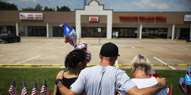 CHATTANOOGA, TN - JULY 18: People look on at a memorial setup in front of the Armed Forces Career Center/National Guard Recruitment Office which had been shot up on July 18, 2015 in Chattanooga, Tennessee. According to reports, Mohammod Youssuf Abdulazeez, 24, opened fire on the military recruiting station at the strip mall on July 16th and then drove more than seven miles away to an operational support center operated by the U.S. Navy and killed four United States Marines and a Navy sailor. The gunman was likely killed in a exchange of gunfire with the police. (Photo by Joe Raedle/Getty Images)