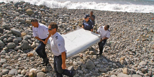 In this photo dated Wednesday, July 29, 2015, French police officers carry a piece of debris from a plane in Saint-Andre, Reunion Island. Air safety investigators, one of them a Boeing investigator, have identified the component as a "flaperon" from the trailing edge of a Boeing 777 wing, a U.S. official said. Flight 370, which disappeared March 8, 2014, with 239 people on board, is the only 777 known to be missing. (AP Photo/Lucas Marie)