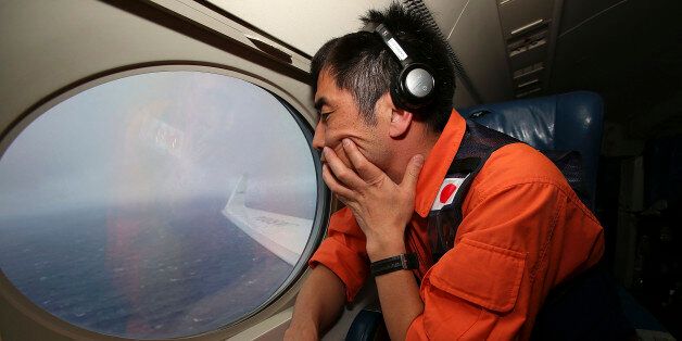 Koji Kubota of the Japan Coast Guard keeps watch through a window of their Gulfstream V aircraft while flying in the search zone for debris from the missing Malaysia Airlines flight MH370 Tuesday, April 1, 2014 off Perth, Australia. Investigators are conducting a forensic examination of the final recorded conversation between ground control and the cockpit of the Malaysian plane before it went missing three weeks ago, the Malaysian government said Tuesday. Meanwhile Australia, which is coordinating the search for the Boeing 777, cautioned that it