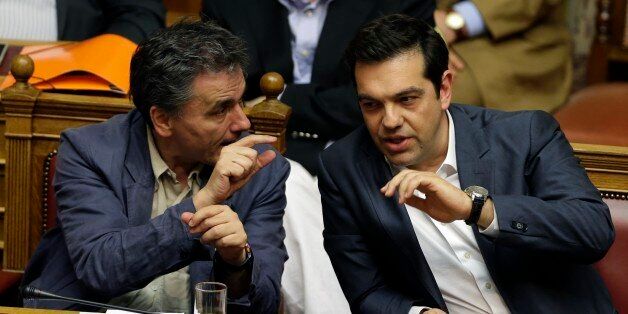 Greece's Prime Minister Alexis Tsipras, right, speaks with Finance Minister Euclid Tsakalotos during a parliament meeting in Athens, Thursday, July 16, 2015. Tsipras was fighting to keep his government intact in the face of outrage over an austerity bill that parliament must pass if the country is to start negotiations on a new bailout and avoid financial collapse. (AP Photo/Thanassis Stavrakis)