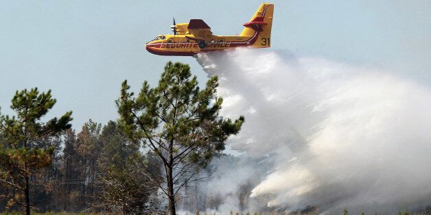 A Canadair plane drops water on a forest fire in Lacanau, southwestern France, Friday, Aug. 17, 2012. French firefighters fought a wildfire on Friday that has destroyed a large swathe of forest and scrubland near a popular seaside and surfing resort in southwestern France. (AP Photo/Bob Edme)