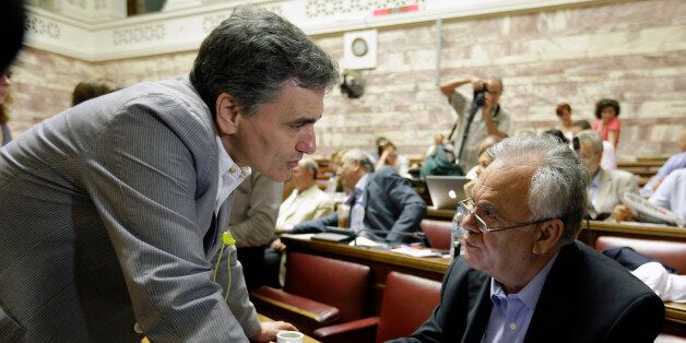 Greek Finance Minister Euclid Tsakalotos, left, speaks with Deputy Prime Minister Giannis Dragasakis before a meeting with lawmakers of Syriza party at the Greek Parliament in Athens, Friday, July 10, 2015. Greece's Prime Minister Alexis Tsipras will seek backing for a harsh new austerity package from his party Friday to keep his country in the euro â less than a week after urging Greeks to reject milder cuts in a referendum. (AP Photo/Thanassis Stavrakis)