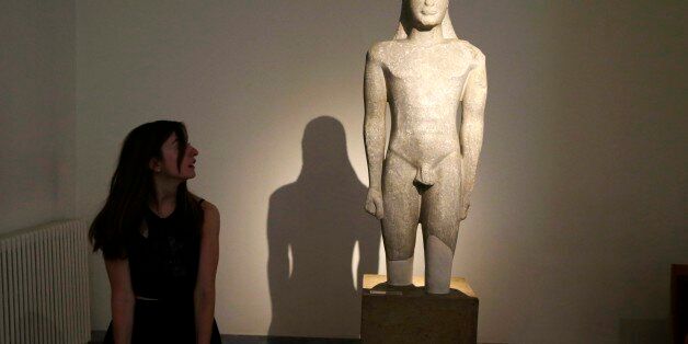 A tourist looks an ancient Greek sculpture of a kouros nude male youth, during the International Day Museum with free entrance for the visitors, at the Archeological museum in Athens on Monday, May 18, 2015. Greeceâs cash-strapped government signaled Monday it needs a deal with bailout lenders by the end of the month to keep up loan repayments though the summer, as renewed concern rattled markets and saw borrowing rates shoot up. (AP Photo/Thanassis Stavrakis)