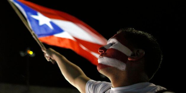 A Puerto Rican fan waves his country's flag as he watches a live telecast of the World Baseball Classic championship game between Puerto Rico and Dominican Republic in San Juan, Tuesday, March 19, 2013. The Dominican Republic beat Puerto Rico 3-0 on Tuesday night at AT&T Park in San Francisco. (AP Photo/Ricardo Arduengo)