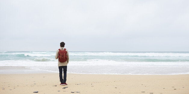 Hiker looking out to sea from beach.