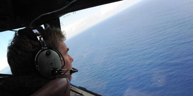 In this April 13, 2014 photo taken from the Royal New Zealand air force (RNZAF) P-3K2-Orion aircraft, co-pilot Squadron Leader Brett McKenzie looks out of a window while searching for debris from missing Malaysia Airlines Flight 370, in the Indian Ocean off the coast of western Australia. The search area for the missing flight will be expanded by another 60,000 square kilometers (23,000 square miles) in the Indian Ocean if the jetliner is not found by May, officials said Thursday, April 16, 2015