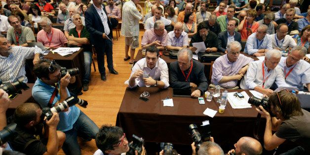 Greek Prime Minister Alexis Tsipras holds a bottle of water as he is surrounded by photographers during a meeting of ruling radical left Syriza party's central committee in Athens, on Thursday, July 30, 2015. Tsipras called for an extraordinary party congress in September, after Greece is expected to seal a new bailout deal with its international creditors, in a bid to end a rebellion by his hardline lawmakers that is threatening to topple his coalition government. (AP Photo/Thanassis Stavrakis)