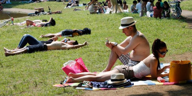 People lie and sunbathe at a park in Tokyo, Sunday, June 1, 2014. Hot weather continues in the metro area as temperature goes up high at 32 degrees Celsius (89 degrees Fahrenheit), according to Japan's meteorological bureau. (AP Photo/Shizuo Kambayashi)