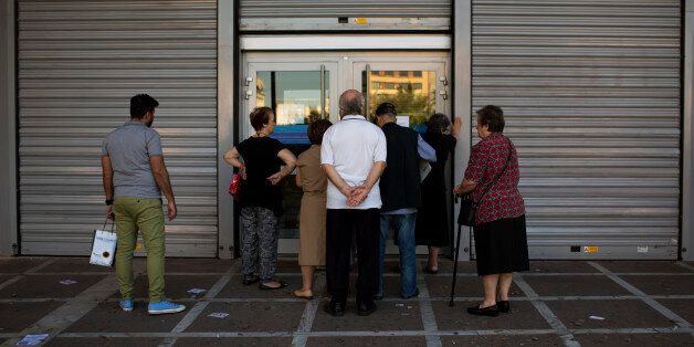 People wait to be allowed into a bank to withdraw a maximum of 120 euros ($134) for the week, in central Athens, Friday, July 3, 2015. As Greek banks and markets remain closed Friday for a fifth day, rival campaigns scrambled to roll out their messages. And a prediction from the International Monetary Fund that Greece will need piles of additional cash from eurozone countries and others over the next three years put even more pressure on the government. (AP Photo/Emilio Morenatti)