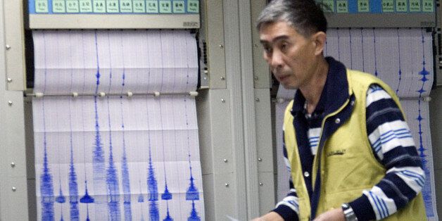 An unidentified official at Taiwan's Central Weather Bureau walks in front of seismograph readings of a 6.7 magnitude earthquake that shook Taiwan, Tuesday, Dec. 26, 2006, in Taipei, Taiwan. The quake, with a preliminary magnitude of between 6.7 and 7.2, was felt throughout Taiwan. It swayed buildings and knocked objects off the shelves in the capital, Taipei. No damage or injuries were immediately reported. (AP Photo)