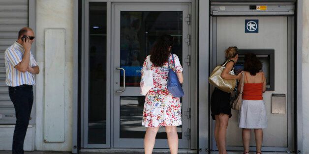The women right use the ATM machine as two other people wait outside of a closed bank in central Athens, Wednesday, July 8, 2015. Frustrated and angry eurozone leaders fearing for the future of their common currency gave the Greek Prime Minister Alexis Tsipras a last-minute chance Tuesday to finally come up with a viable proposal on how to save his country from financial ruin. (AP Photo/Petros Karadjias)
