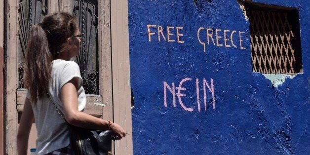 A woman walks past a slogan written on a wall in Athens on July 7, 2015. Eurozone leaders will hold an emergency summit in Brussels on July 7 to discuss the fallout from Greek voters' defiant 'No' to further austerity measures, with the country's Prime Minister Alexis Tsipras set to unveil new proposals for talks. AFP PHOTO / LOUISA GOULIAMAKI (Photo credit should read LOUISA GOULIAMAKI/AFP/Getty Images)