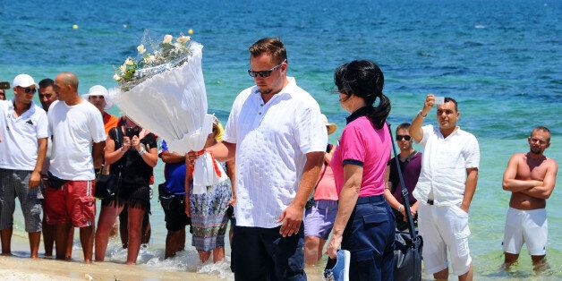 Unidentified tourists lay flowers to honor the victims of a deadly beach attack a week ago that killed 38 people, near the Imperial Marhaba hotel in the Mediterranean resort town of Sousse, Friday, July 3, 2015. Eight people are in custody in Tunisia, suspected of having direct links to a deadly beach attack that killed 38 people, but four other possible suspects have been released, a minister said Thursday. (AP Photo/Hassene Dridi)