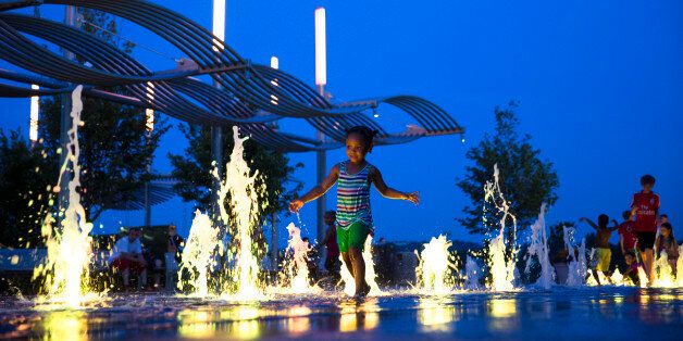 Children play in an illuminated fountain at Smale Riverfront Park in Cincinnati, Monday, June 22, 2015. The park is part of a five-phase revitalization of the Ohio riverfront as the downtown area undergoes a resurgence with investors and businesses moving into once vacant lots and buildings. (AP Photo/John Minchillo)