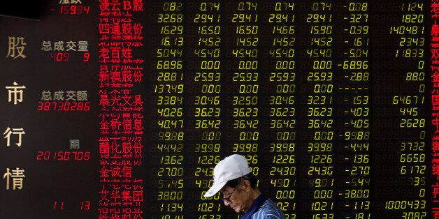 A man walks past an electric board displaying stock prices at a brokerage house in Beijing, China, Wednesday, July 8, 2015. China's central bank has promised more credit to finance stock trading in the latest move aimed at stopping a plunge in stock prices that has prompted hundreds of companies to suspend trading in their shares. (AP Photo/Andy Wong)