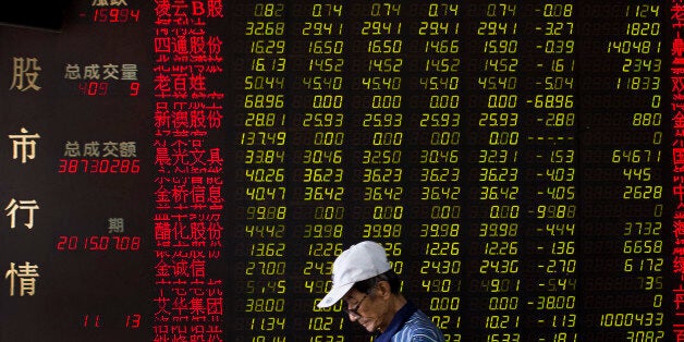 A man walks past an electric board displaying stock prices at a brokerage house in Beijing, China, Wednesday, July 8, 2015. China's central bank has promised more credit to finance stock trading in the latest move aimed at stopping a plunge in stock prices that has prompted hundreds of companies to suspend trading in their shares. (AP Photo/Andy Wong)