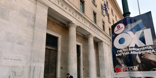 People walk past the Bank of Greece's headquarters and a poster for upcoming referendum by ruling party Syriza reading ''NO for democracy and dignity'' in Athens on July 1, 2015. Nearly one in two Greeks intend to vote 'No' in a weekend referendum on the terms of its bailout, but capital controls are boosting the 'Yes' camp, a poll showed today. Prime Minister Alexis Tsipras has called on Greeks to vote 'No' in the plebiscite, which will ask voters whether they want to accept the latest deal from Athens' creditors -- a deal he has branded 'humiliating'. AFP PHOTO / LOUISA GOULIAMAKI (Photo credit should read LOUISA GOULIAMAKI/AFP/Getty Images)